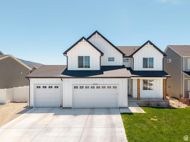 modern inspired farmhouse featuring concrete driveway, board and batten siding, a front yard, and a shingled roof