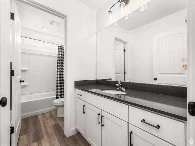 bathroom featuring toilet, vanity, shower / bath combo with shower curtain, and wood finished floors