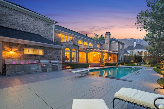 2428 E Field Rose Dr, Holladay, UT 84121 - pool at dusk with a patio area, area for grilling, a diving board, and an outdoor pool