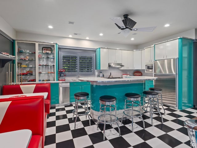 2428 E Field Rose Dr, Holladay, UT 84121 - kitchen featuring light floors, a breakfast bar area, under cabinet range hood, white cabinetry, and appliances with stainless steel finishes