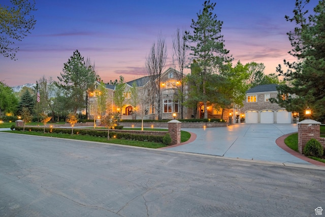 view of front of house with stone siding, curved driveway, and a garage