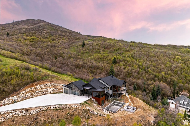 aerial view at dusk featuring a forest view and a mountain view