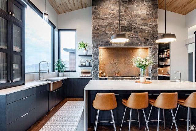 kitchen featuring a sink, a kitchen breakfast bar, dark wood-type flooring, wooden ceiling, and vaulted ceiling
