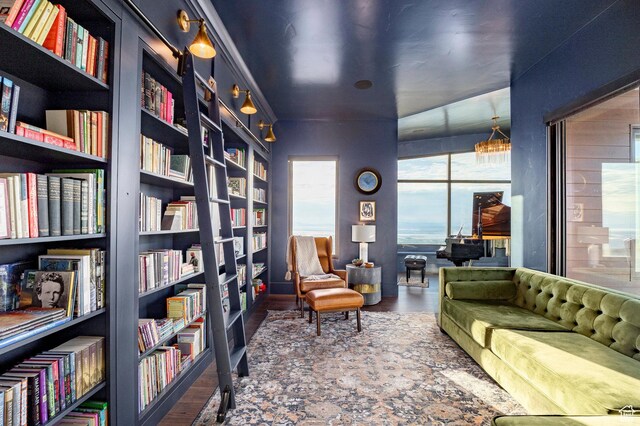 living area with built in features, wall of books, and wood finished floors