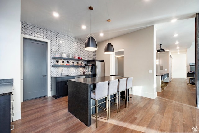 kitchen featuring dark countertops, stainless steel appliances, wood finished floors, and a kitchen bar