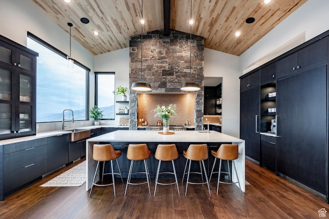 kitchen with a sink, wooden ceiling, light countertops, an island with sink, and a kitchen bar
