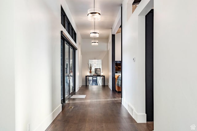 corridor featuring baseboards, visible vents, and dark wood finished floors