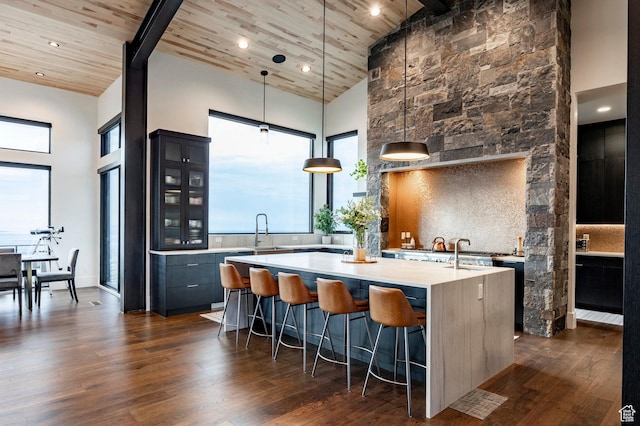 kitchen featuring a breakfast bar area, wood ceiling, high vaulted ceiling, light countertops, and a kitchen island with sink