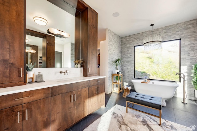bathroom featuring tile patterned floors, an inviting chandelier, a freestanding bath, and vanity