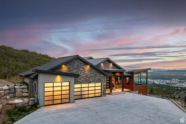 contemporary home with a garage, stone siding, driveway, and stucco siding