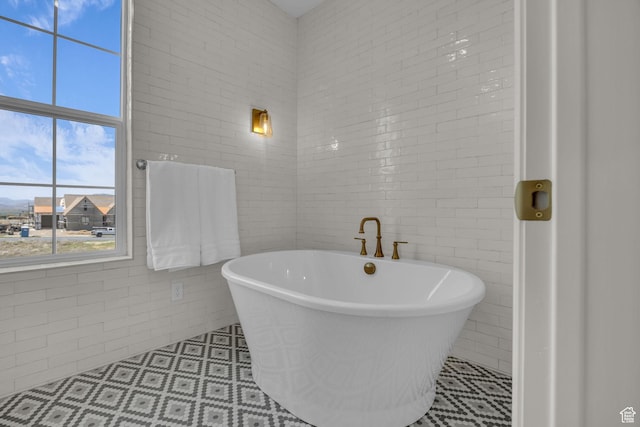 full bath featuring tile walls and a freestanding tub