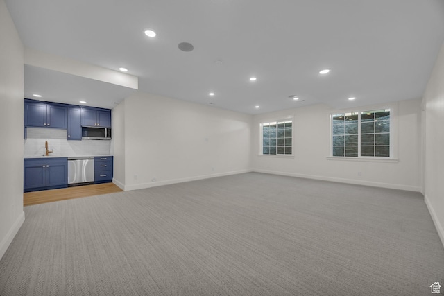 unfurnished living room with baseboards, light carpet, recessed lighting, and a sink