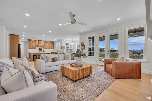 living room featuring a ceiling fan, baseboards, light wood-style flooring, and recessed lighting