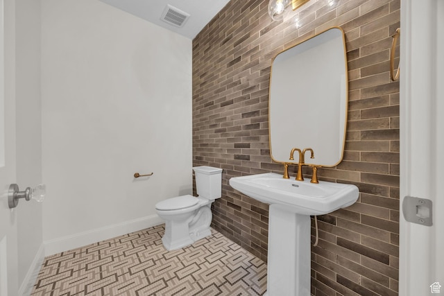 half bathroom with toilet, visible vents, and baseboards
