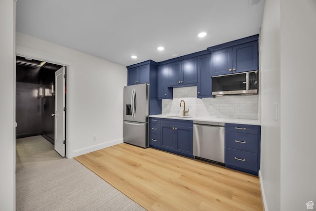 kitchen with light countertops, stainless steel appliances, blue cabinetry, and a sink