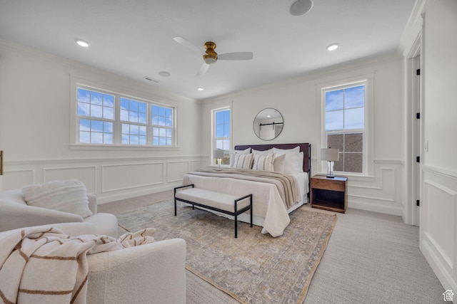 carpeted bedroom featuring a decorative wall and multiple windows