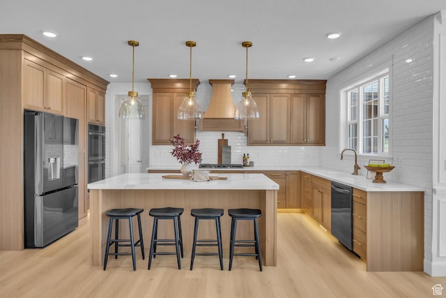 kitchen featuring light wood-style flooring, custom exhaust hood, a sink, a kitchen island, and stainless steel appliances