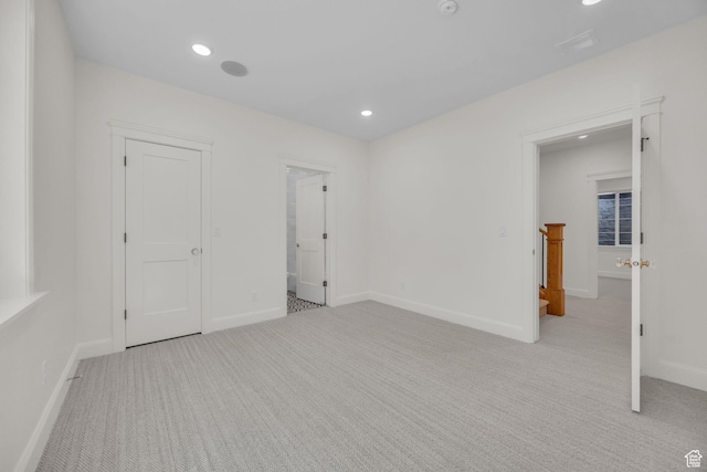 empty room with light carpet, baseboards, and recessed lighting