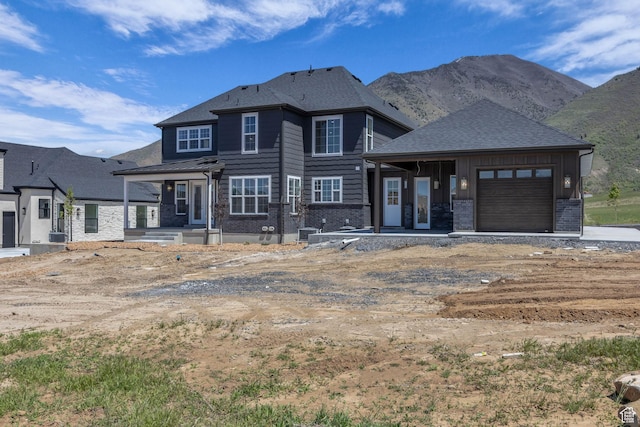 view of front of house featuring an attached garage, a mountain view, brick siding, and cooling unit