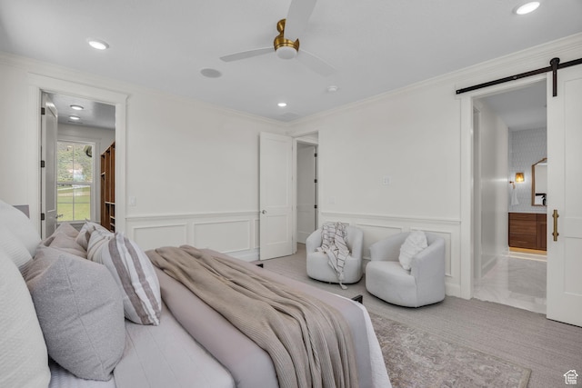 bedroom with recessed lighting, a barn door, a decorative wall, connected bathroom, and light carpet