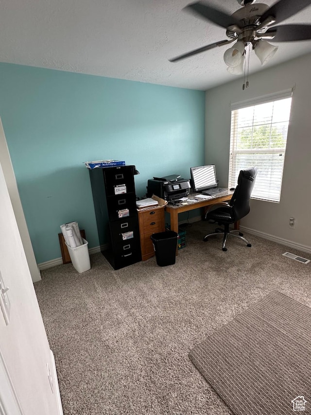 office space featuring a textured ceiling, visible vents, carpet flooring, a ceiling fan, and baseboards
