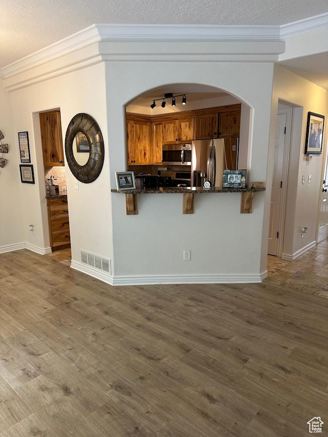kitchen with crown molding, brown cabinetry, visible vents, and appliances with stainless steel finishes
