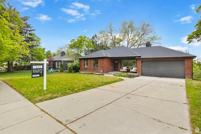 view of front of property featuring an attached garage, a chimney, concrete driveway, a front lawn, and brick siding