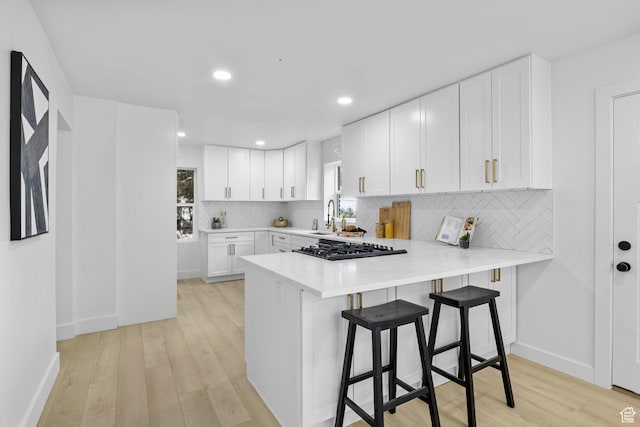kitchen featuring black gas cooktop, light wood finished floors, white cabinetry, and light countertops