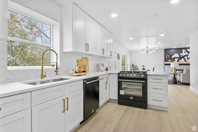 kitchen with a peninsula, a sink, white cabinets, black appliances, and decorative backsplash