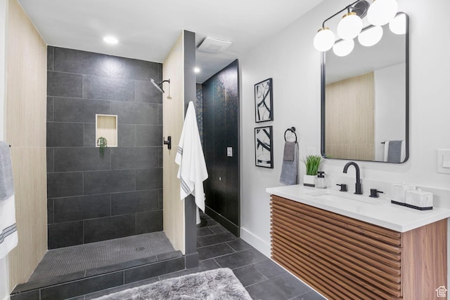 bathroom with tile patterned floors, baseboards, vanity, and a tile shower