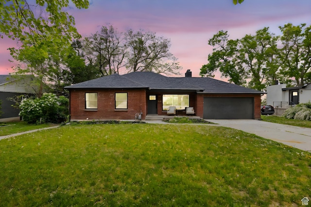 ranch-style house with a chimney, brick siding, a garage, concrete driveway, and a front yard