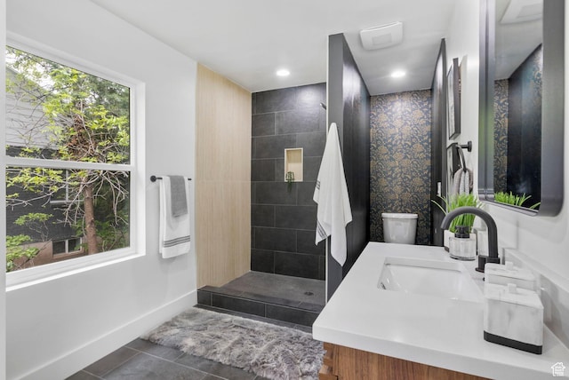 bathroom featuring tile patterned floors, vanity, baseboards, and tiled shower