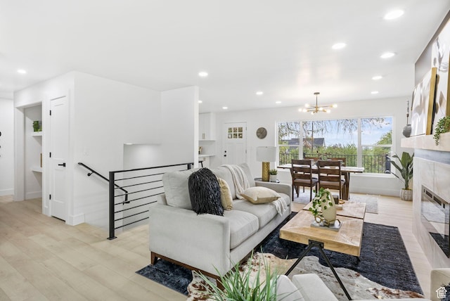 living area with a chandelier, baseboards, light wood-type flooring, and recessed lighting