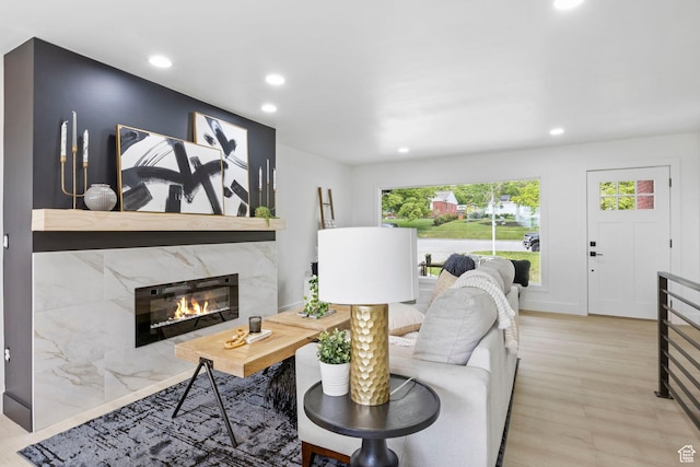 living room featuring recessed lighting, a high end fireplace, and light wood-style floors