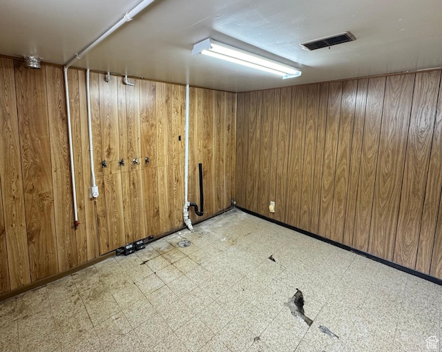 finished below grade area featuring light flooring and wooden walls
