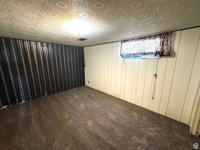 basement with carpet floors, wooden walls, and an ornate ceiling
