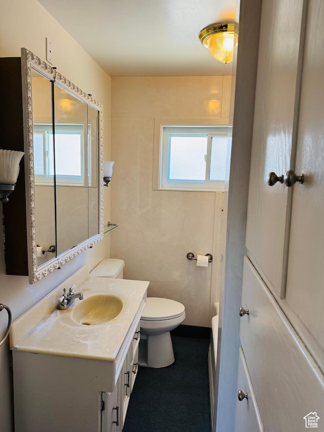 bathroom featuring healthy amount of natural light, toilet, and vanity