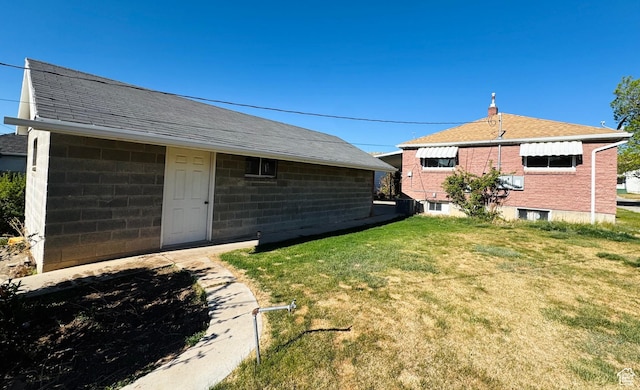 back of house featuring a lawn and a shingled roof