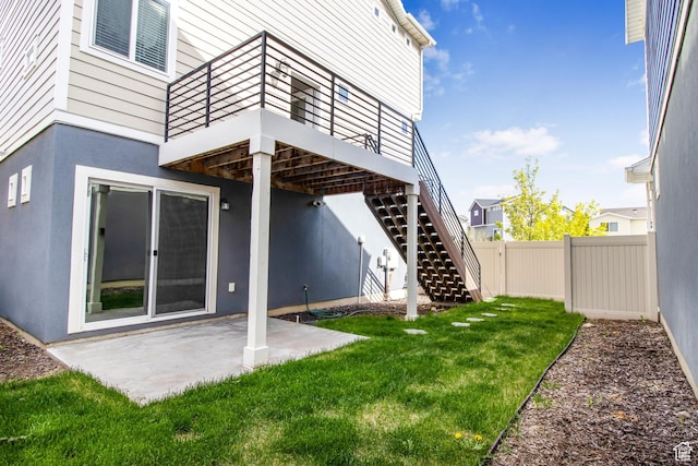 rear view of property featuring a patio area, stairs, fence, and a lawn