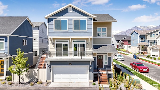 view of front facade with fence, a mountain view, driveway, a residential view, and a garage
