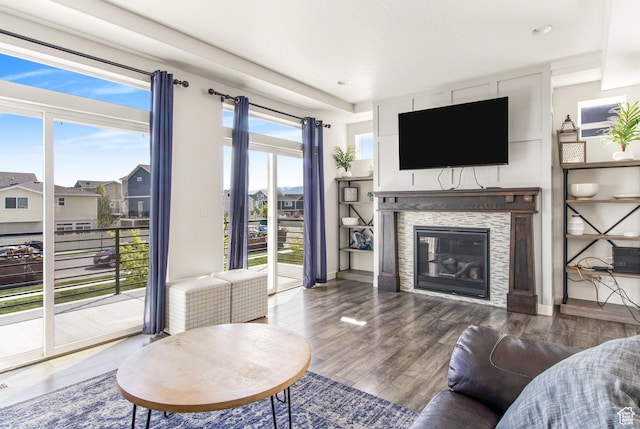 living area with recessed lighting, a glass covered fireplace, and wood finished floors