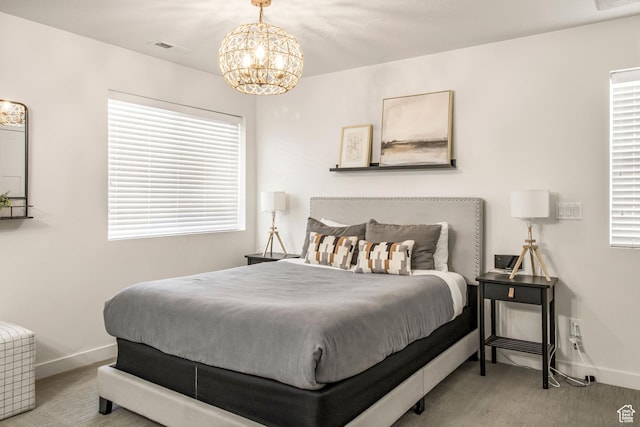 carpeted bedroom with multiple windows, a chandelier, baseboards, and visible vents