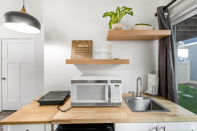 interior space featuring open shelves, butcher block counters, a sink, and white microwave