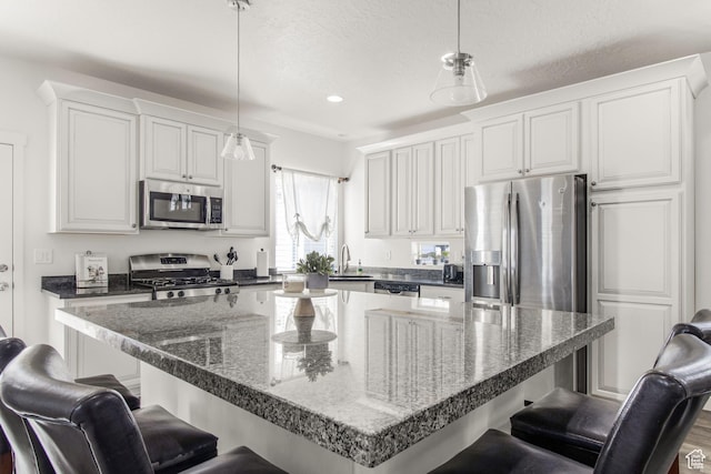 kitchen with appliances with stainless steel finishes, a kitchen breakfast bar, and white cabinetry