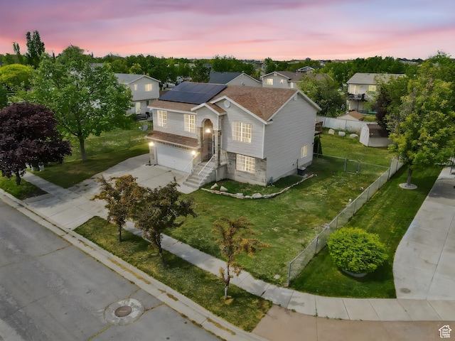 view of front of house with concrete driveway, a garage, a front yard, fence private yard, and solar panels