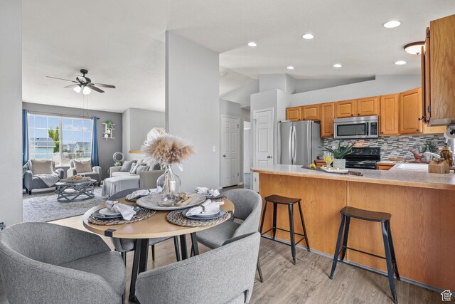 dining area with light wood-type flooring, lofted ceiling, a ceiling fan, and recessed lighting