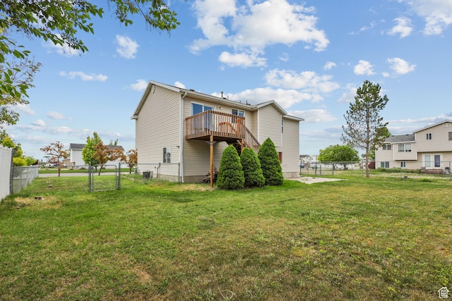 back of house with a yard, a wooden deck, a fenced backyard, and a gate
