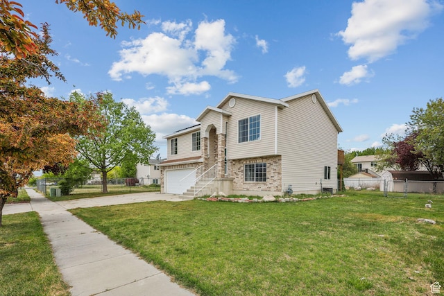 split level home featuring an attached garage, driveway, fence, and a front lawn