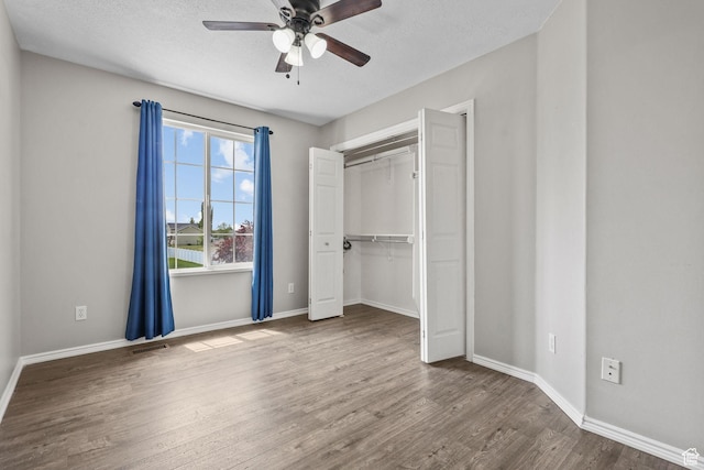 unfurnished bedroom with a closet, baseboards, visible vents, and wood finished floors