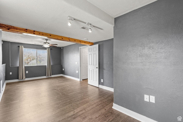 empty room featuring visible vents, dark wood finished floors, a textured wall, a ceiling fan, and baseboards